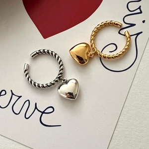 Macro detail of gold and silver twisted hoop earrings with heart charms on card