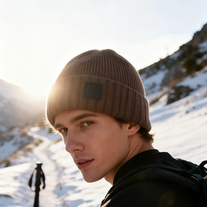 Outdoor winter knitted beanie in dark brown with mountain logo and snow mountain background