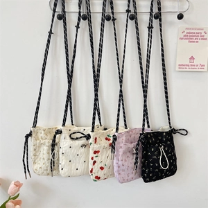 Detailed close-up of floral and cherry pattern canvas crossbody bags with drawstring