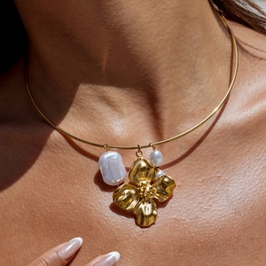 Detail of 18K gold stainless steel necklace with baroque pearl and flower charm on model