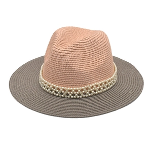 Detail of peach pink straw hat with dark grey brim and decorative white pearl beads