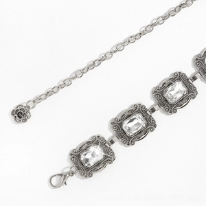 Détail de la ceinture chaîne argentée vintage avec des cristaux de taille émeraude