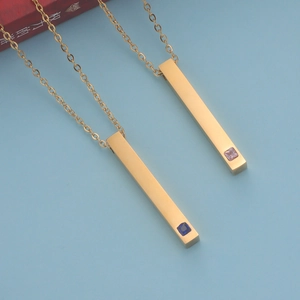 Detailansicht goldener Stabanhänger mit blauen und rosa Kristallen an feinen Ketten