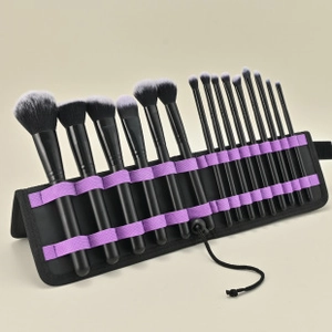 Detail of 14-piece makeup brush set with black handles in a purple strap roll bag