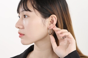 Close-up of a model wearing minimalist silver stainless steel hoop earrings for women