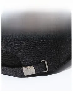 Close-up of the metal adjustment buckle and tweed texture on a gray outdoor baseball cap
