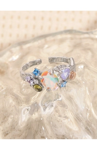 Macro detail of silver open ring featuring multi-colored gemstones and moonstone texture