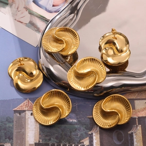Elegant gold drop earrings with wavy and pleated textures displayed on a metallic tray