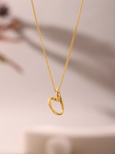 Detailed view of irregular hollow heart pendant on a gold necklace with elegant shadows
