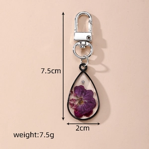 Detailed view of teardrop resin keychain with purple dried flowers and dimensions