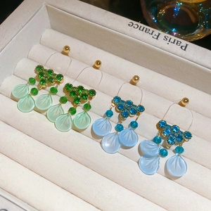 Detail view of crystal floral tassel earrings in green and blue on jewelry box