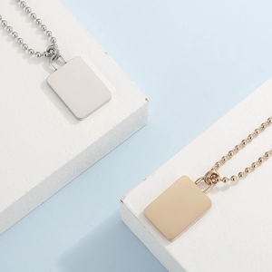 Detail of 18K gold and silver rectangle pendant necklaces on stylish bead chains