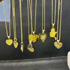 Detailed close-up of gold titanium steel heart and angel pendants with engraved messages