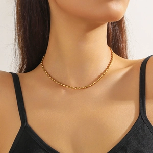 Close-up of a gold-plated olive ball chain necklace worn on a woman's neck