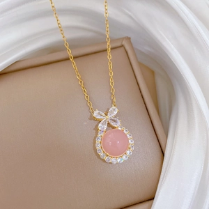 Macro shot of gold necklace featuring a pink gemstone pendant and sparkling crystal bow detail