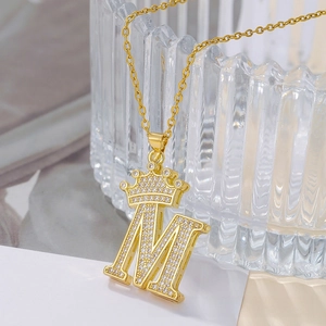 Macro shot of gold-plated letter M necklace with crown detail and sparkling zircon inlay