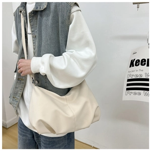 Detailed view of cream pleated dumpling bag in soft leather on model for casual wear