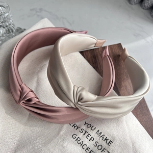 Detail showing two wide knotted headbands in rose pink and champagne satin fabrics
