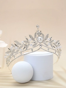 Close-up of silver bridal crown with rhinestones and pearls on elegant beige background