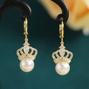 Macro shot of gold crown pearl earring with clear cubic zirconia on a black stand