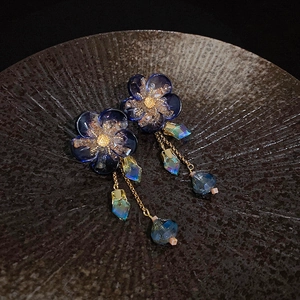 Detail of blue flower earrings with gold tassel chains and crystal drop pendants