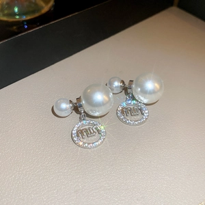 Macro view of sterling silver zircon letter earrings with large white pearls and round charms