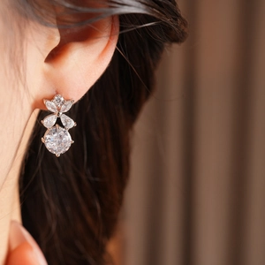 Gros plan de boucles d'oreilles fleurs en argent serties de zircons clairs