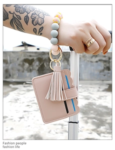 Pink silicone beaded wristlet keychain with tassel and leather card holder on luggage handle