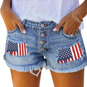 Close-up of denim shorts featuring American flag patches, frayed edges and button fly