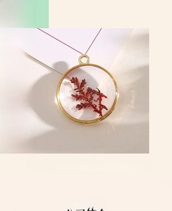 Macro view of gold alloy pendant featuring red dried flower encapsulated in resin