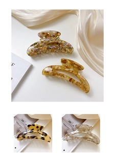 Detail of acetate hollow moon hair claws in amber, yellow, and leopard print textures