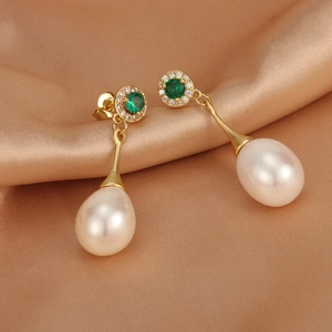 Macro shot of 18K gold plated freshwater pearl earrings with green stones on silk background