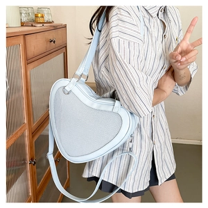 Detailed view of light blue heart-shaped ITA bag with mesh front on a female model