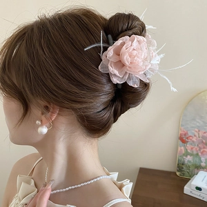 Nahaufnahme der rosa Organza Blumen-Haarklammer mit Federn an einem Haarknoten