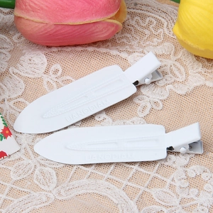Close-up of two white lacquered metal hair clips on beige lace with tulip decoration