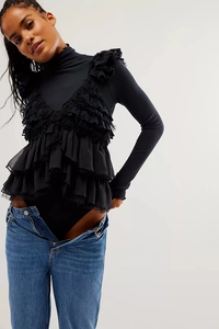 Detail of black waffle-knit bodysuit with intricate lace ruffles and floral embroidery