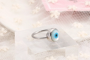 Detailed shot of silver evil eye ring featuring a blue inset on acrylic stand