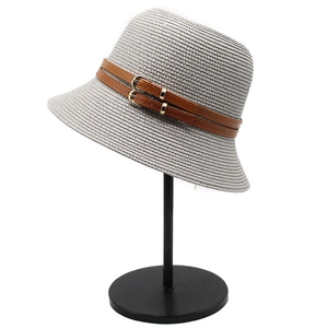 Detail of gray woven sun hat featuring double brown faux leather straps and gold buckle