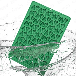 Detailed view of dark green silicone Christmas tree baking mold being rinsed under splashing water
