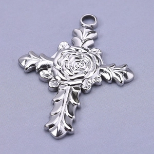Macro detail of a silver stainless steel cross pendant with intricate rose flower relief