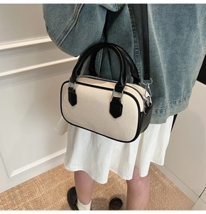 Detail of a minimalist black and white woven Boston bag with premium leather handles