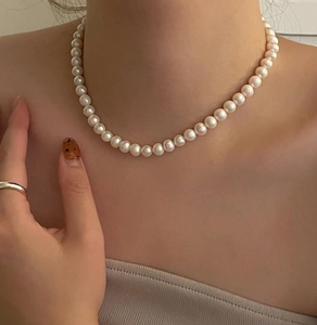 Detailed close-up of a 10mm white pearl necklace worn as a minimalist choker on a model