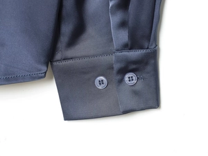 Close-up of blue satin shirt sleeve cuffs with polished gray buttons and glossy fabric