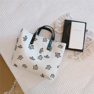Détails de broderie papillon sur sac cabas en toile crème avec poignées en cuir