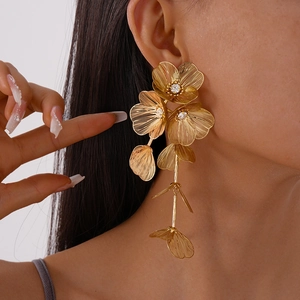 Close-up of long gold floral mesh earrings with sparkling rhinestones on model