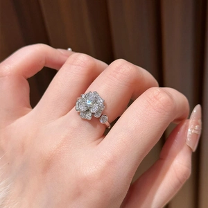 Detailed view of silver camellia flower ring with zircons worn by a model on finger