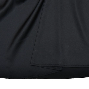 Detail of irregular hemline and stitching on a sleek black backless maxi dress