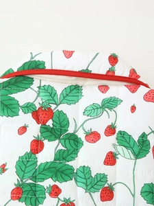 Detail of diamond quilted fabric with strawberry print and vibrant red piping trim