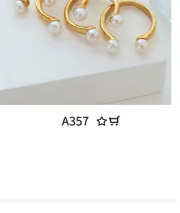 Macro detail of gold-plated open rings featuring white round pearls on minimalist texture