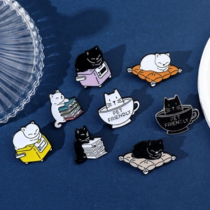 Close-up of eight cute cartoon cat enamel pins in various poses on a dark blue surface